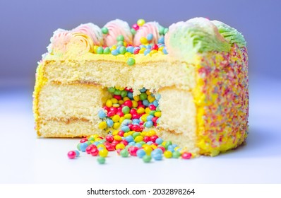 Madeira sponge coated with yellow colour frosting, layered with plum  jam, filled and topped with multicolour chocolate nibs and decorated with multicolour frostings and sugar decorations, pinata cake