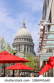 Madison Downtown Cityscape. Sunny Spring Day Street View With State Capitol Building And Outdoor Cafe Bright Red Umbrellas On A Foreground. City Of Madison, Wisconsin, Midwest USA.