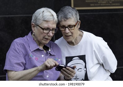 MADISON, WISCONSIN USA - JUNE 6: An Older Lesbian Couple Sharing The News Via Their Phone  After A Judge Struck Down Wisconsin's Gay Marriage Ban On Friday June 6, 2014 In Madison, WI