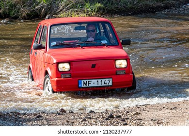 Madona, Latvia - May 01, 2021: red oldtimer car Fiat 126 overcomes water obstacle