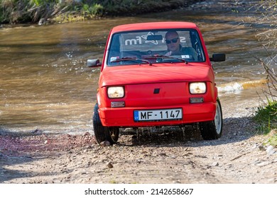 Madona, Latvia - May 01, 2021: red oldtimer car Fiat 126 overcomes water obstacle