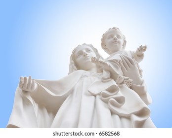 Madonna and Jesus child - from below white statue of holy Virgin Mary mother of the child Jesus on background of blue sky