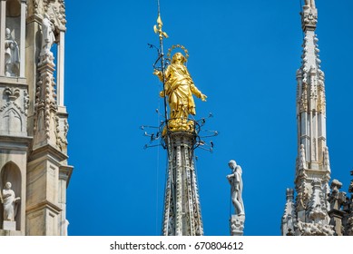 Madonna or Madonnina on Milan Cathedral top at height of 108.5 m, Milan, italy. Statue on roof against blue sky close-up. Milan Cathedral or Duomo is landmark of Milano city. Luxury rooftop view.