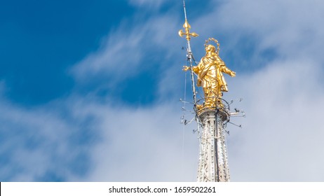The Madonnina atop Milan Cathedral timelapse in Milan, italy. Close up view. Blue cloudy sky at summer day. This statue was erected in 1762 at the height of 108.5 m.