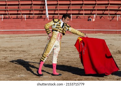 Madrid, Spain- April 30, 2022: Bullfight in San Martin de Valdeiglesias. Bullfighter with a crutch. Fighting bull. Bullfighter giving a muleta pass to the bull in a bullring.