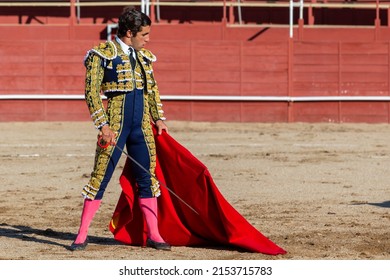 Madrid, Spain- April 30, 2022: Bullfight in San Martin de Valdeiglesias. Bullfighter with a crutch. Fighting bull. Bullfighter giving a muleta pass to the bull in a bullring.