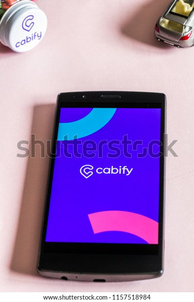 MADRID, SPAIN -\
AUGUST 16, 2018. Cabify app on a mobile phone on light pink\
background. Cabify is an spanish company that provices vechicles\
for hire via it\'s smartphone mobile\
app.