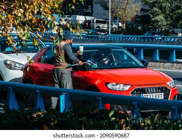 Madrid, Spain - December 6, 2021: Middle Aged Man Of South Asian Appearance Working By Washing Car Windows With A Windshield Wiper (squeegee) In Madrid, Spain. M30 Highway