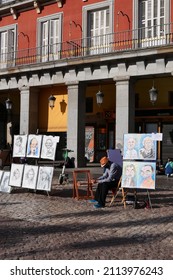 Madrid Spain January 2022. Street Artist. Main Square. Old City Centre. Sunny. Columns. Drawings. Person Sitting Down.