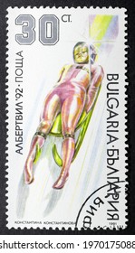 MADRID, SPAIN - JANUARY 30, 2021. Vintage Stamp Printed In Bulgaria Shows Toboggan For Albertville '92, The 1992 Winter Olympics