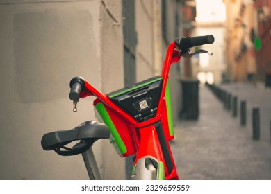 Madrid, Spain. July 1, 2022 A red green electric bicycle from Lime plus Uber is parked on the sidewalk in a city street. Eco-friendly safe share transport, bike for rent in an urban environment. 
