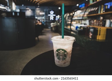 Madrid, Spain. June 1, 2022. A plastic cup with the Starbucks logo with a cool coffee drink, smoothie, lemonade inside is on the table at the popular coffee chain. Cold drink in cafe, dark background.