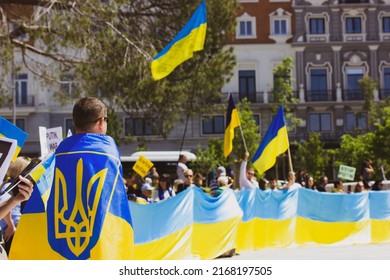 Madrid, Spain. May 8, 2022. Rally to support Ukraine in war with Russia. A crowd of people with yellow blue Ukrainian flags. A man wrapped in flag with a trident. Protesters against Russia invasion.