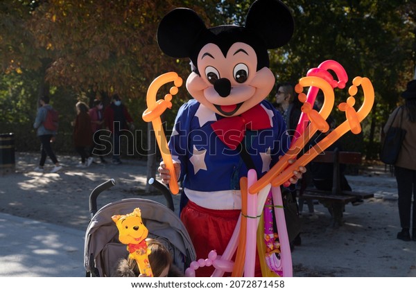 A street performer dressed as Micky Mouse, poses with a child. 