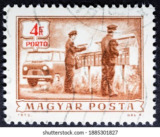 MADRID, SPAIN - OCTOBER 3, 2020. Vintage Stamp Printed In Hungary Shows Postal Services, Rural Mail Delivery, Two Postmen Laid Out Letters To Mailboxes