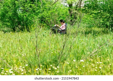 Madrid, Spain;05012022: Old Lady Reading The Newspaper On The Grass In The Middle Of The Field