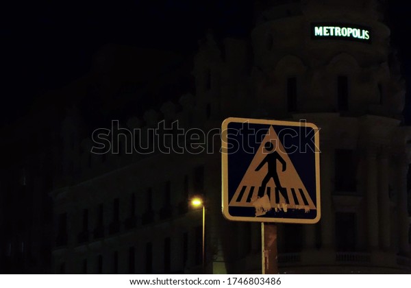 Madrid/Spain - October 22th, 2019:\
Pedestrian crossing street sign in front the Metropolis\
Building.