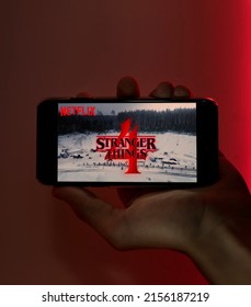  MADURAI, INDIA 15 MAY 2022 : Stranger Things 4 from Netflix TV series Poster, hands holding the mobile with shot of Stranger Things Season 4.