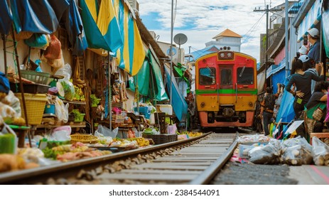 Maeklong Railway Market Thailand, Train on Tracks Moving Slow. Umbrella Fresh Market on the Railroad Track, Mae Klong Train Station, Bangkok, a famous railway market in Thailand - Powered by Shutterstock