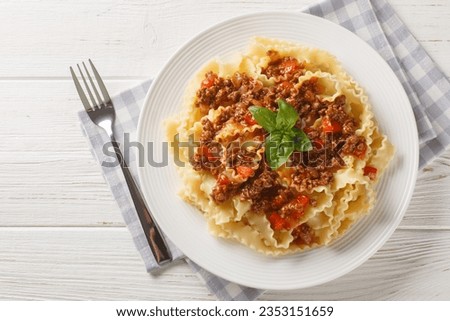 Mafalde or Mafalda or Mafaldine Pasta Bolognese closeup on the plate on the white wooden table. Horizontal top view from above
