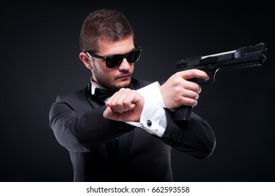 Mafioso in suit aiming pistol at his target being ready to shoot isolated on black background