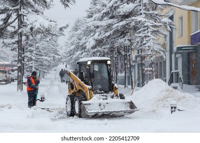 Magadan, Magadan Region, Siberia, Russia - November 8, 2021. Snow Removal On The Street During A Snowfall. A Lot Of Snow On The Sidewalk After A Snowstorm. Cold Snowy Weather In The Northern City.