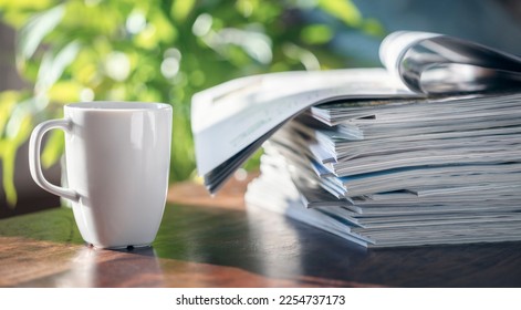 Magazine pile and coffee cup on table in cafe or home living room background - Powered by Shutterstock