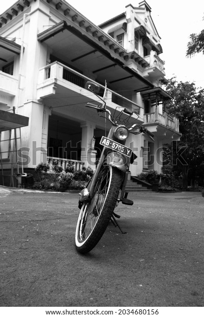 Magelang,\
Central Java, Indonesia (12 August 2021): a classic DKW motorbike\
is in front of an old church building in Dutch architectural style\
that still stands firmly surrounded by a\
garden