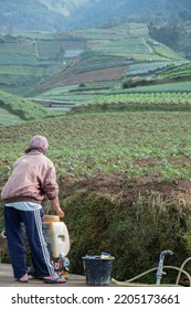 Magelang, Indonesia, 11, September, 2022, Young Farmer Preparing Organic Fertilizer With Manual Pump Tank Wearing Old Hat And Red Jacket