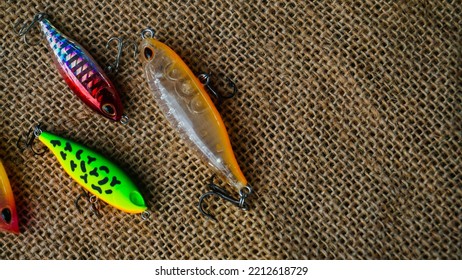 Magelang, Indonesia - October 9th 2022 : Artificial Lure Made From Plastic For Fishing By Casting. Casting Lure With Hook On The Burlap. Artificial Lure With The Shape Of Minnow - Flat Lay