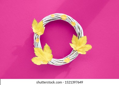 Magenta Of Fuchsia Color Paper Flat Lay With Decorative Wattle Wreath Decorated With Yellow Autumn Leaves