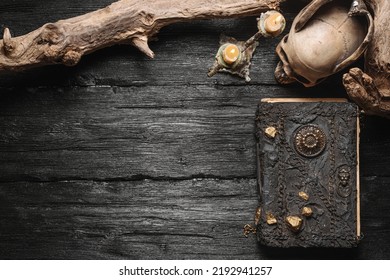 Magic book, skull and burning candle on the old wooden table background with copy space. - Shutterstock ID 2192941257