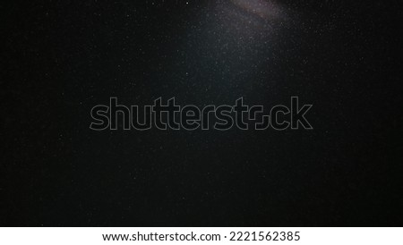 A magic cloud of dust floating in space on a black background. Particles sparkle and shimmer in studio light. Macro shot of texture whites snow, smoke, steam, fog with glare luminosity.