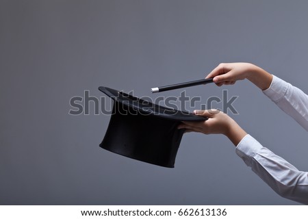 Magic hat and wand in child hands - against grey background with copy space