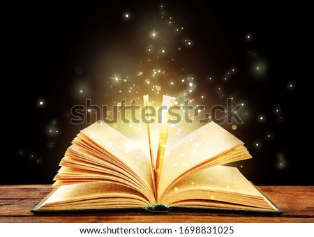 Magic light emanating from open old book on table