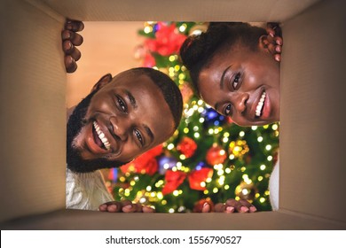 Magic Moments. Excited African American Couple Opening Christmas Present At Home, View From Inside Of Box.