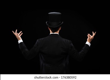 magic, performance, circus, show concept - magician in top hat showing trick from the back