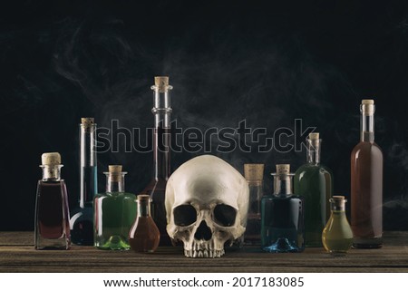 Magic potion and human skull on magic table background. Witchcraft concept. Halloween background. Bottles with poison. Witch workspace.