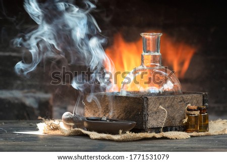 Magic potion on the table on burning fire in fireplace background. Alchemy concept.