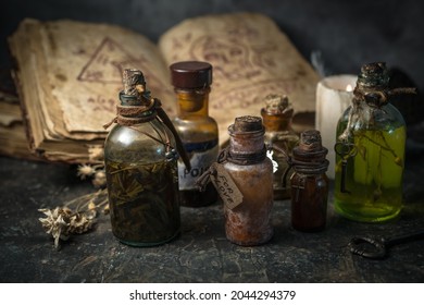 Magic potions in bottles, ancient books and witchery herbs on wooden background, Halloween theme
