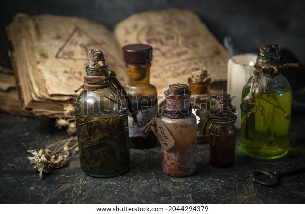 Magic potions in bottles,\
ancient books and witchery herbs on wooden background, Halloween\
theme