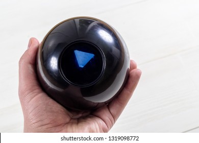 Magic prediction eight ball in hand, on the white background.