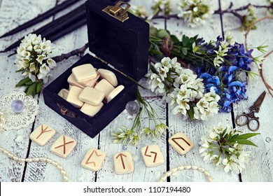 Magic runes in black box with spring wildflowers and decorations on table. Runes are ancient Scandinavian letters, no foreign words in the image