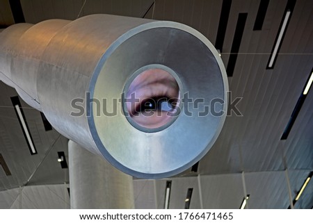 Magic of science.  A child looking through a small eyepiece and one eye is magnified to the other end in a large scale. 