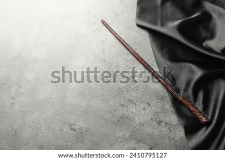 Magic wand and dark cloth on light grey background, top view. Space for text