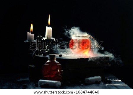 Magic and wizardry concept. Set of sorcery book, magic potions and candles on table. Health potion with vapor streaming from bottle. Alchemy concept.