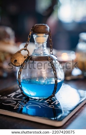 Magical blue elixir bottle secured with a small padlock, styled as an alchemical fantasy prop. Decorative potion bottle inspired by RPG, fantasy games, cosplay and LARP costumes, with mystical and gothic aesthetics.