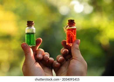 Magical elixirs of a potion in bottles holding in hands on background - Shutterstock ID 2034091415