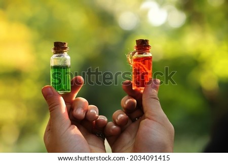 Magical elixirs of a potion in bottles holding in hands on background