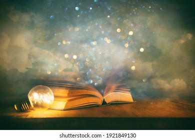 Magical image of open antique book over wooden table with glitter overlay - Shutterstock ID 1921849130